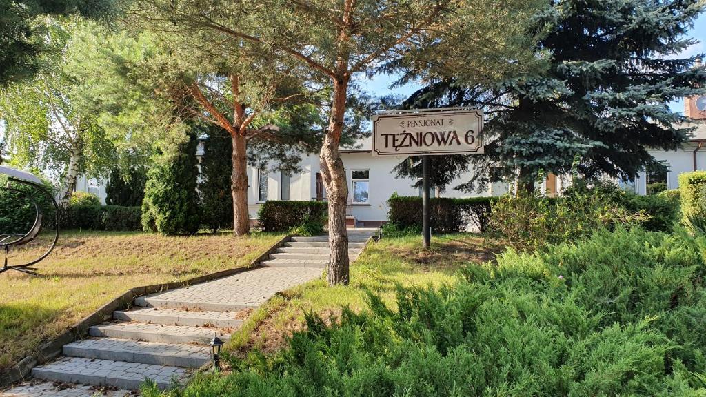 a sign in front of a house with a street sign at Pensjonat Tężniowa 6 in Ciechocinek