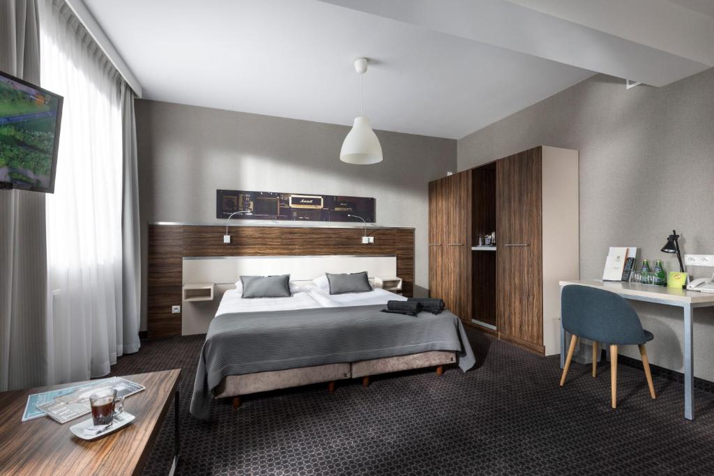 a bedroom with a bed and a table and a desk at Hotel Beethoven in Gdańsk