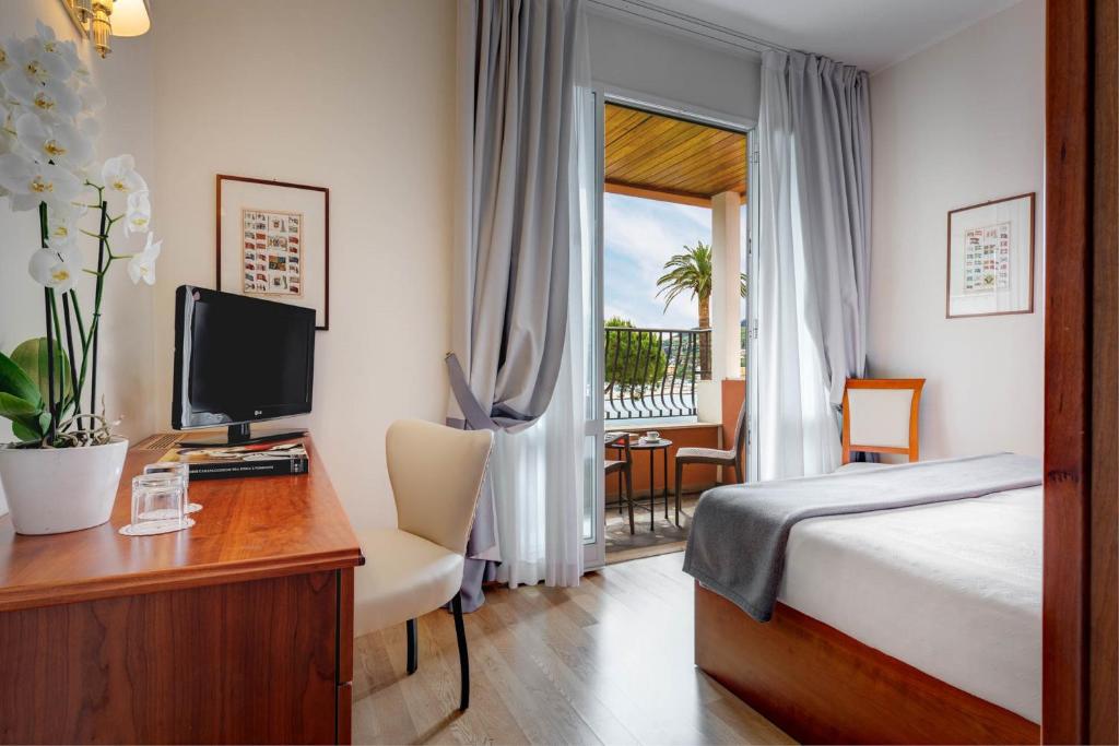 a bedroom with a bed and a desk with a television at Hotel Continental in Santa Margherita Ligure