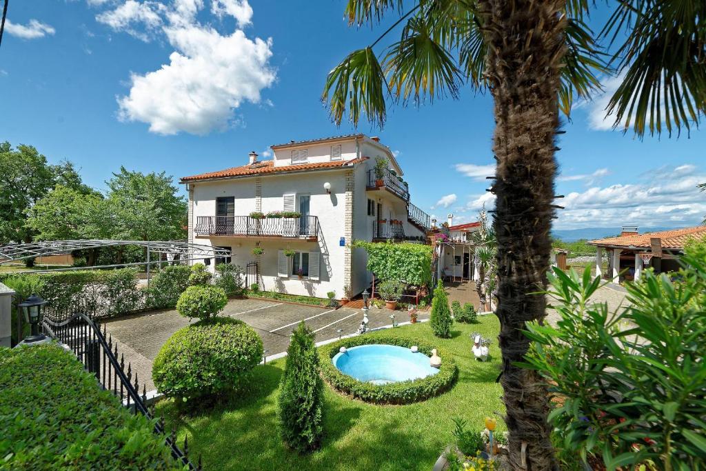 a villa with a swimming pool and a palm tree at Apartments Kata in Malinska