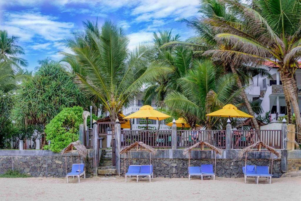 a group of chairs and umbrellas on the beach at Tharanga Surfing Villa in Ahangama