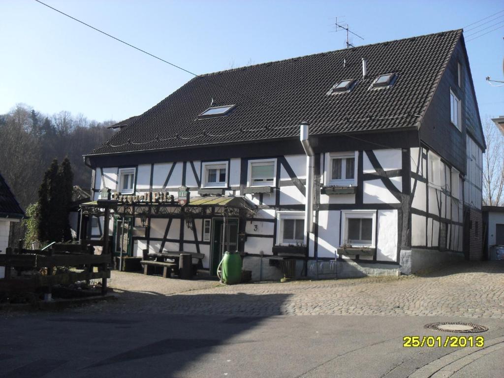 une maison blanche et noire avec un toit noir dans l'établissement Gasthof Zum Stausee, à Engelskirchen