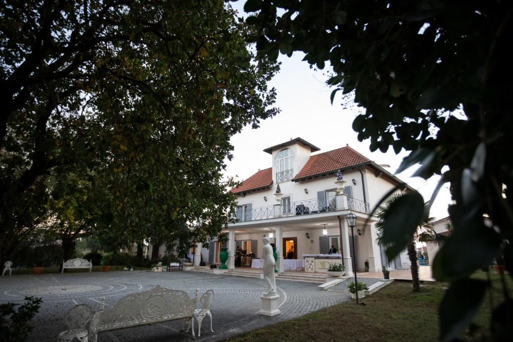 una grande casa bianca con una statua davanti di Villa Strampelli a Pomezia