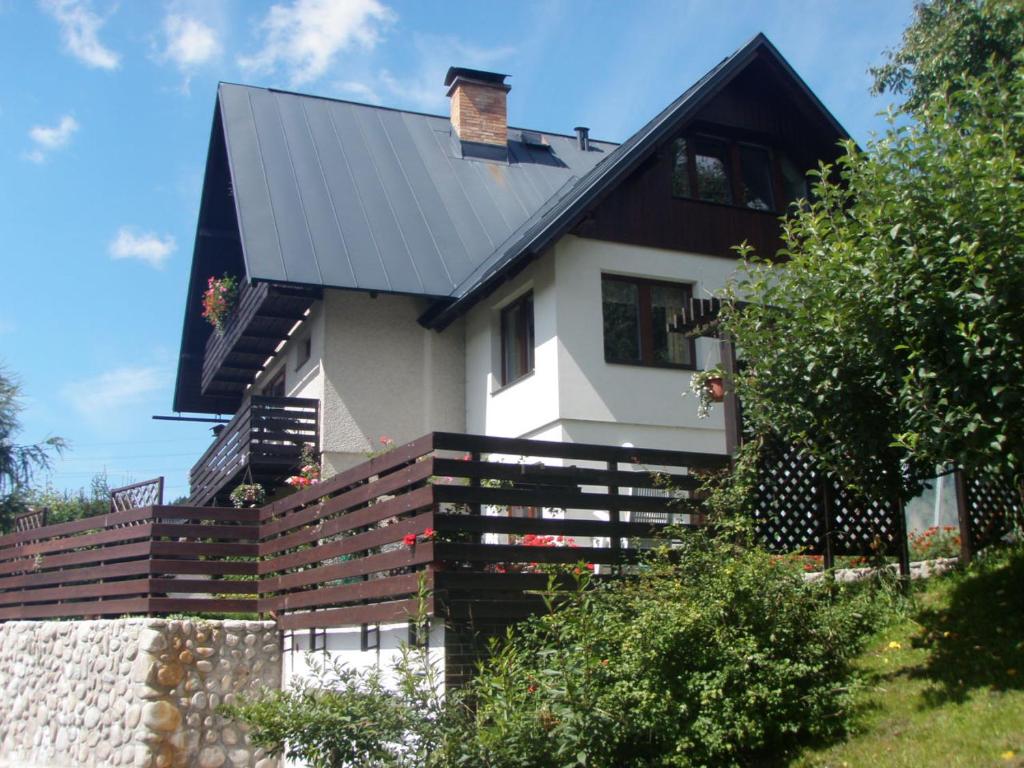 a house with a black roof and a wooden fence at APARTMÁN BERAN in Rokytnice nad Jizerou