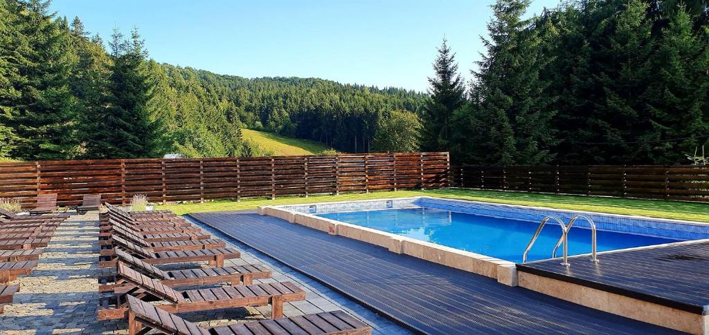 a swimming pool in a yard with a wooden fence at Vilele SuperSki in Cavnic