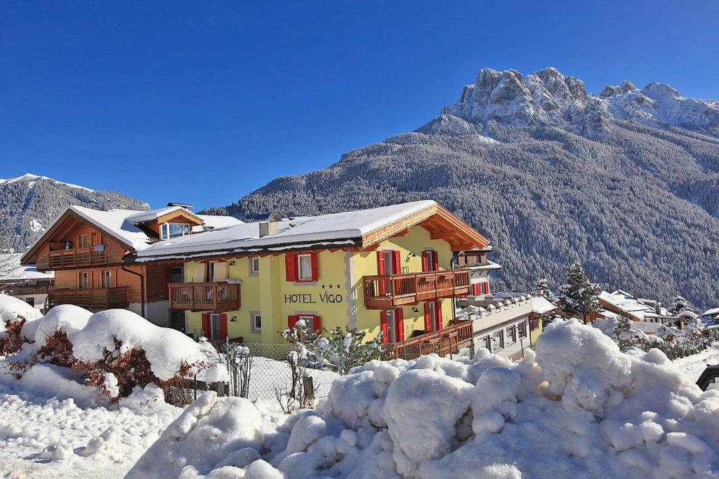 dom w śniegu przed górą w obiekcie Hotel Vigo w mieście Vigo di Fassa