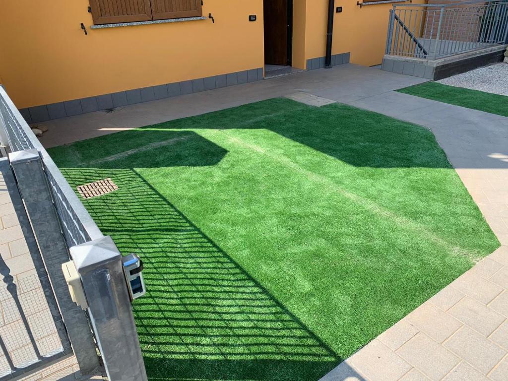 a green artificial grass yard in front of a building at Trilocale in villetta piano terra indipendente in Osio Sotto