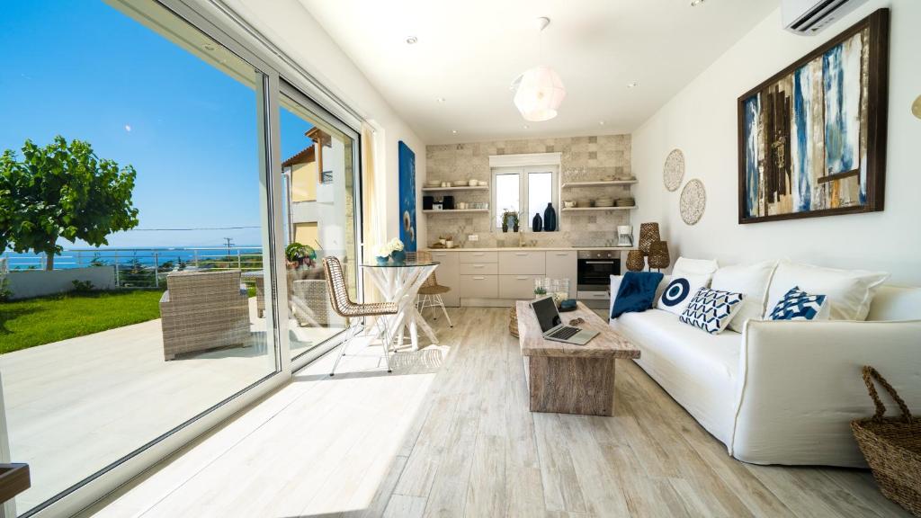 Sala de estar con sofá blanco y vistas al océano en Villa Erythrous, en Stavromenos