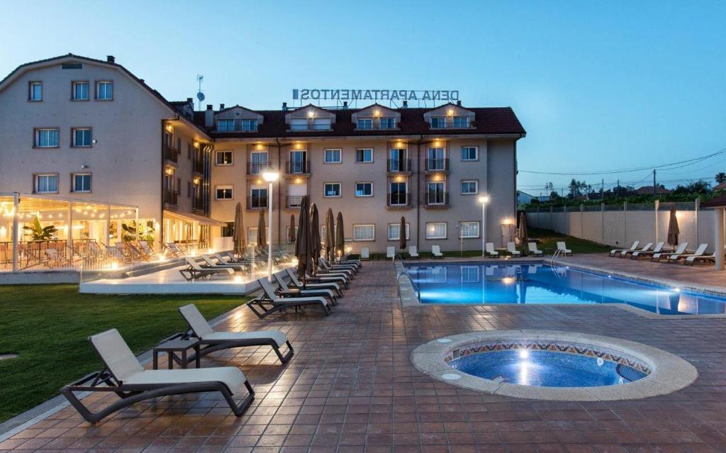 um hotel com cadeiras e uma piscina em frente a um edifício em Apartamentos Dena em Coirón