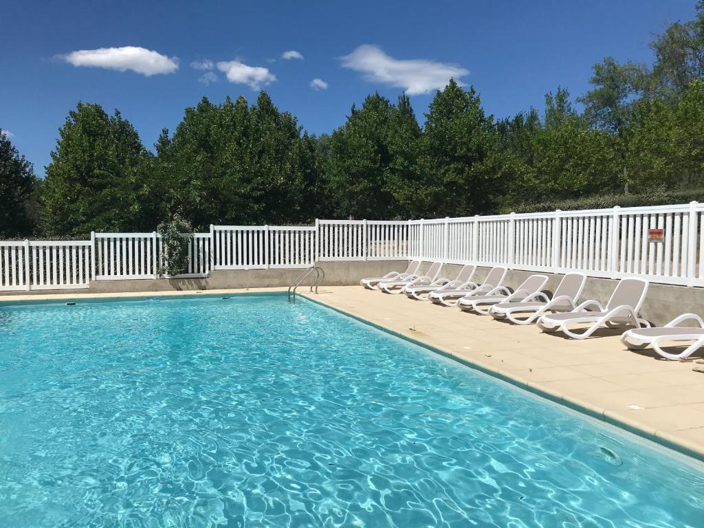 une piscine avec des chaises longues et une clôture dans l'établissement LES BASTIDES DE CHANTERAINE Bungalows, Lodges & Spa, à Aiguines