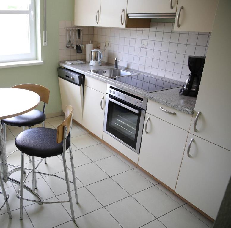una cucina con mobili bianchi, un lavandino e un tavolo di Haus Agnes FeWo 2 a Malborn