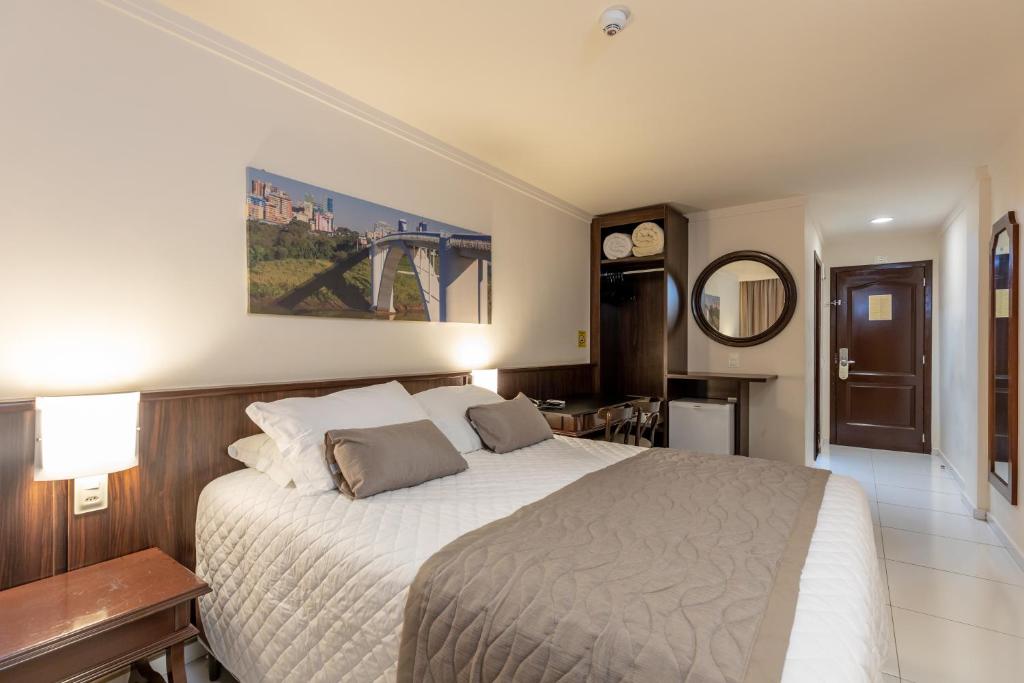 a bedroom with a large bed and a mirror at Bogari Hotel in Foz do Iguaçu