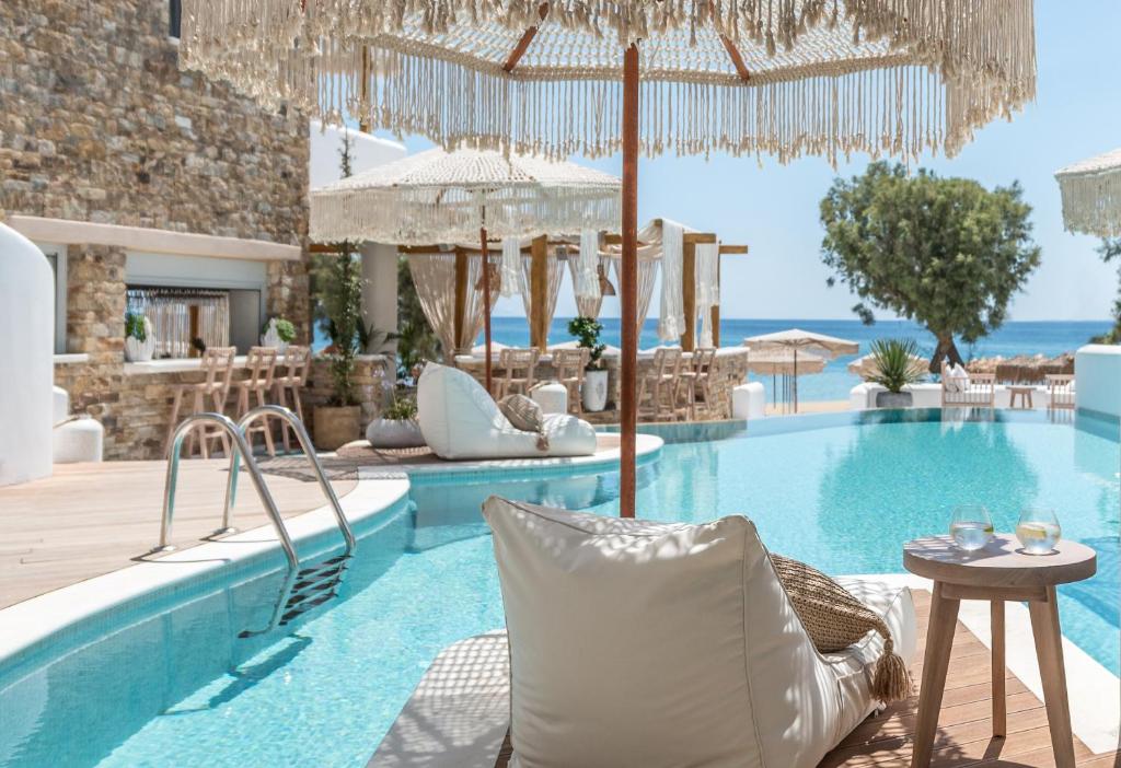 a resort pool with chairs and a table at Virtu Suites in Agios Prokopios