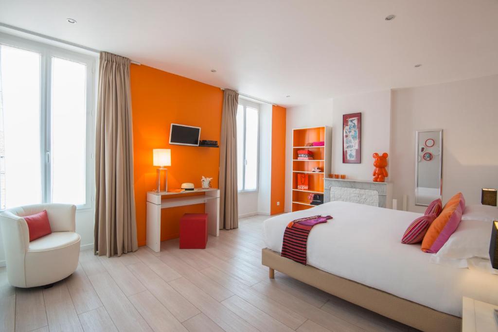 een slaapkamer met een groot wit bed en een stoel bij O Carré Croisette Cannes in Cannes
