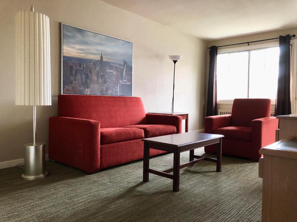 sala de estar con sofá rojo y 2 sillas en Beausejour Hotel Apartments/Hotel Dorval, en Dorval