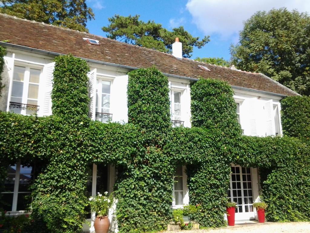 an ivy covered house with white windows at La Petardière in Meaux