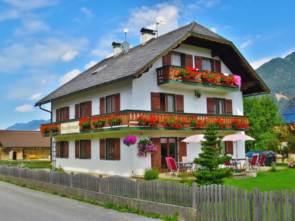 une maison blanche avec des fleurs devant elle dans l'établissement Haus Christoph, à Abersee
