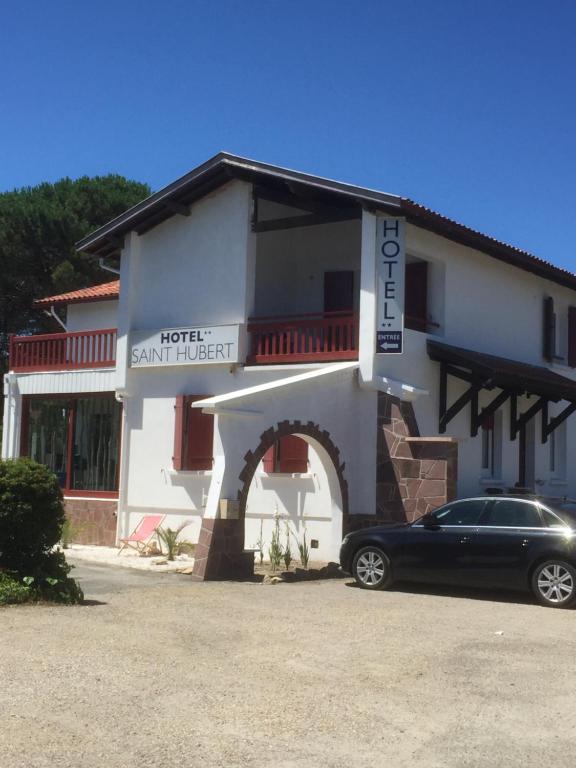 a car parked in front of a building at Hôtel Saint Hubert in Biscarrosse