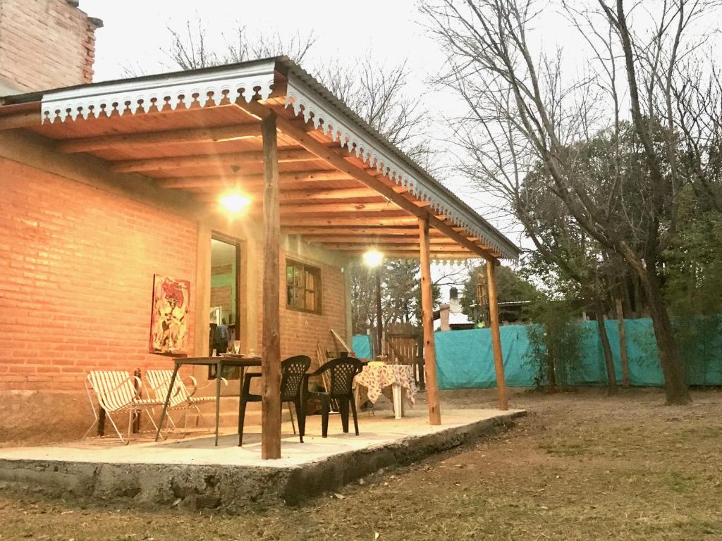 un pabellón con sillas y una mesa en el patio en Pintoresca Cabaña Céntrica a pasos del río en Mina Clavero