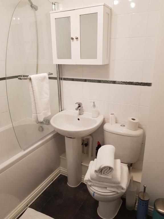 Baño blanco con lavabo y aseo en Vetrelax Basildon Crosse Apartment, en Basildon