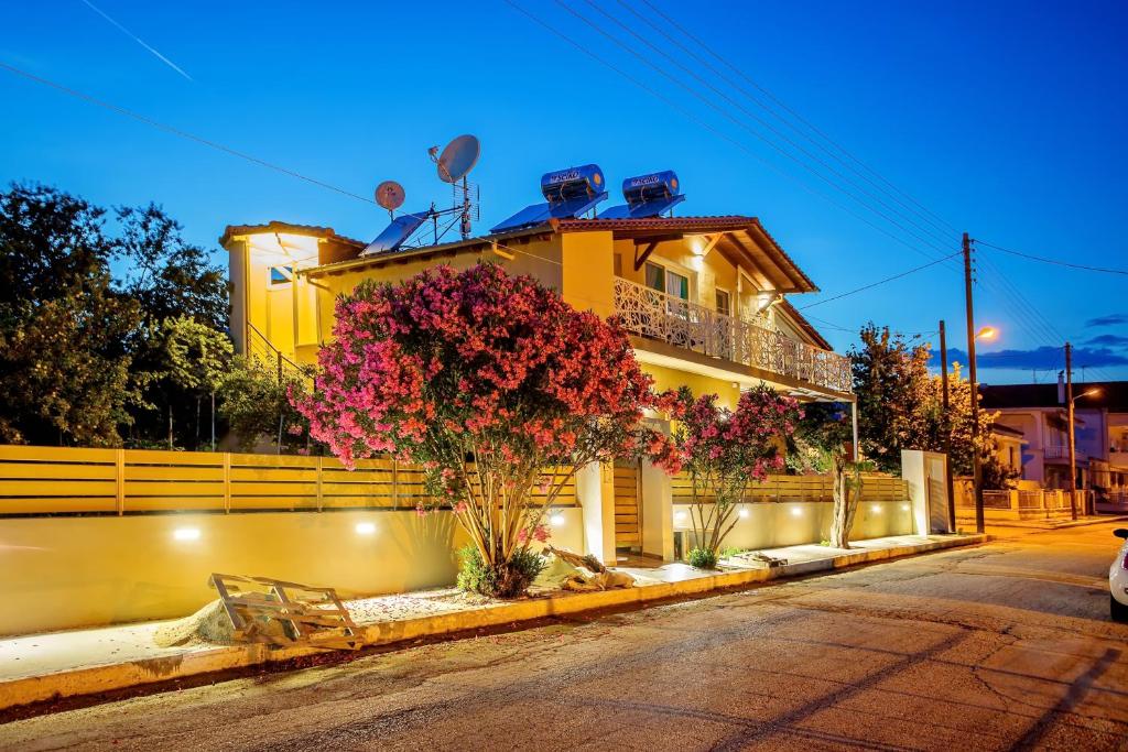 ein gelbes Haus mit Blumen davor in der Unterkunft Lazy Lizard in Néa Karváli