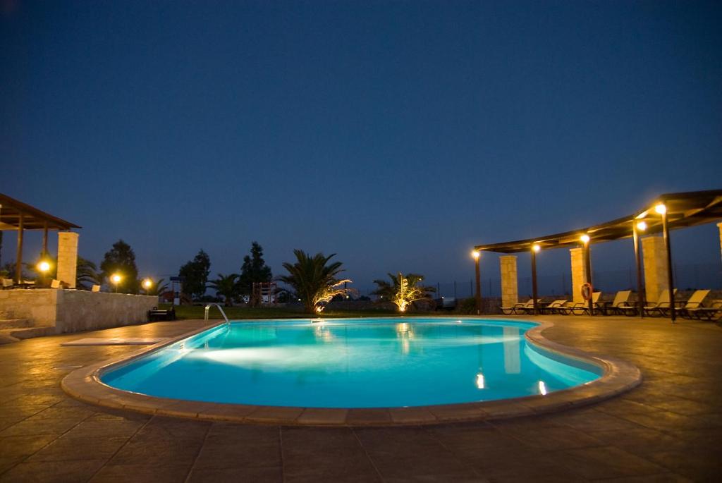 a swimming pool at night with lights on at Kallicrates Village in Frangokastello