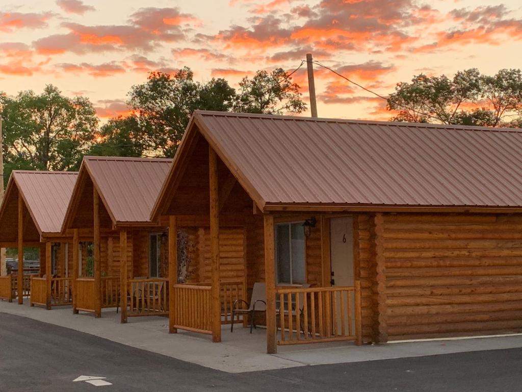 a row of wooden cabins with a sunset in the background at Countryside Cabins in Panguitch