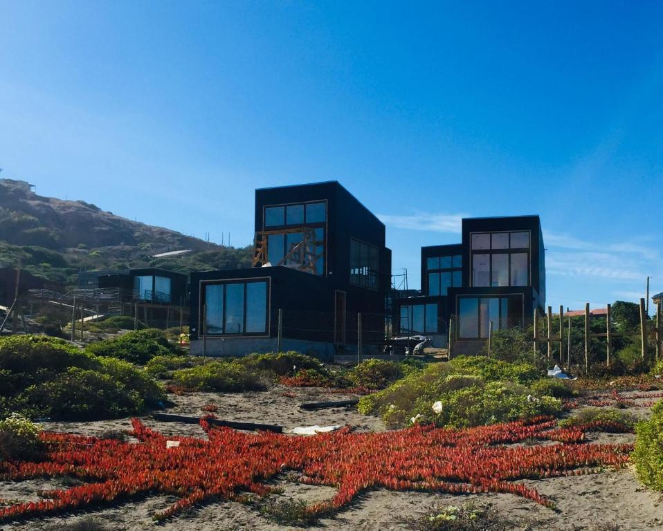 Dois edifícios negros com plantas vermelhas à frente. em PUPUYA LODGE cabaña A, Matanzas em Matanzas