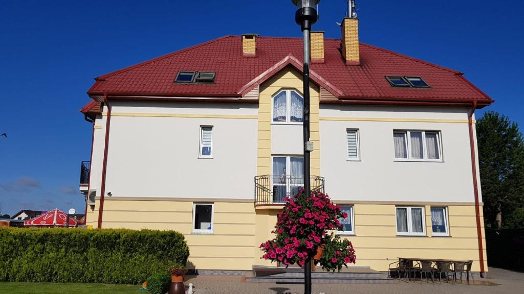 a yellow and white house with a red roof at LAZUR in Gąski