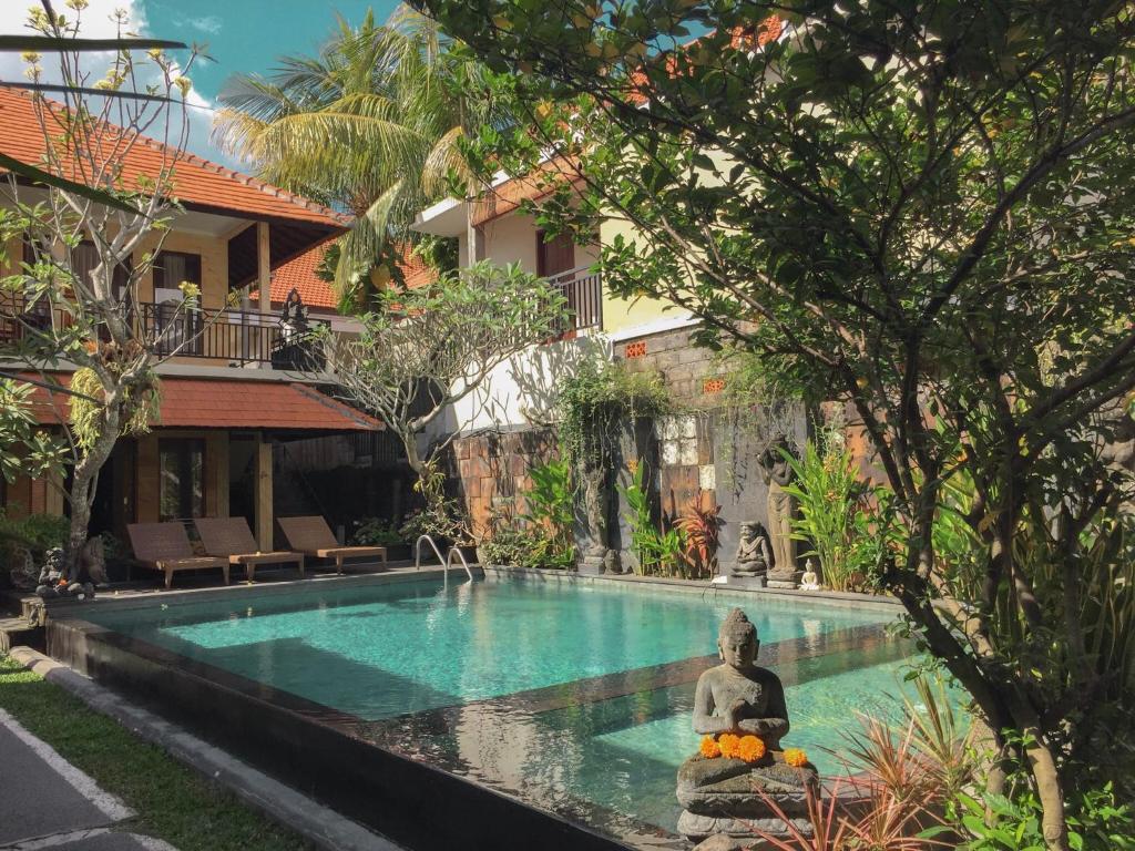 a pool with a statue in front of a house at Merthayasa Bungalows in Ubud