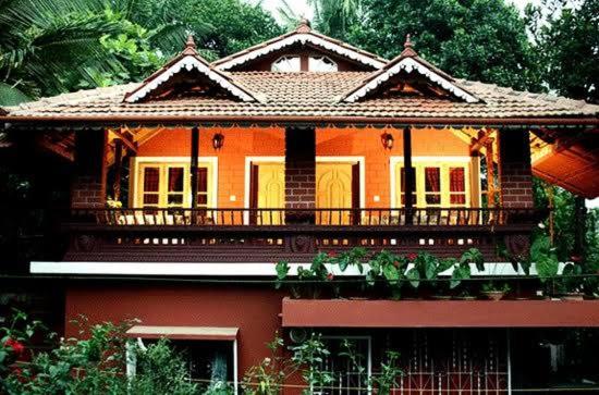a large orange house with a balcony on it at The Four Seasons in Kalpetta