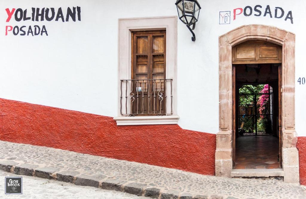 un edificio blanco y rojo con puerta y ventanas en Posada Yolihuani en Pátzcuaro