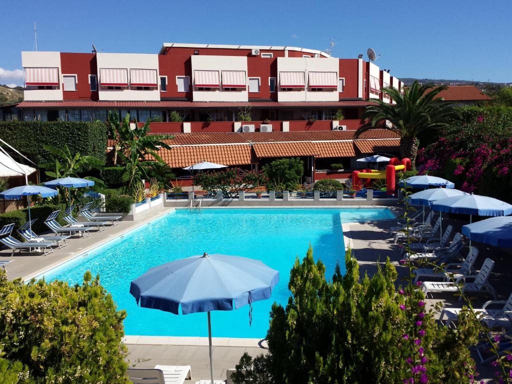 a swimming pool with umbrellas and chairs and a building at Residence Hotel Felix in Ricadi