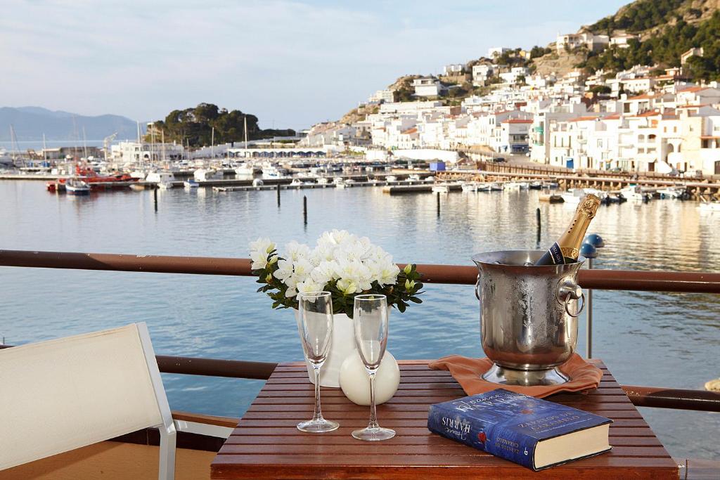 una mesa con dos copas de vino y un libro en un barco en Hotel Spa Cap de Creus en Port de la Selva