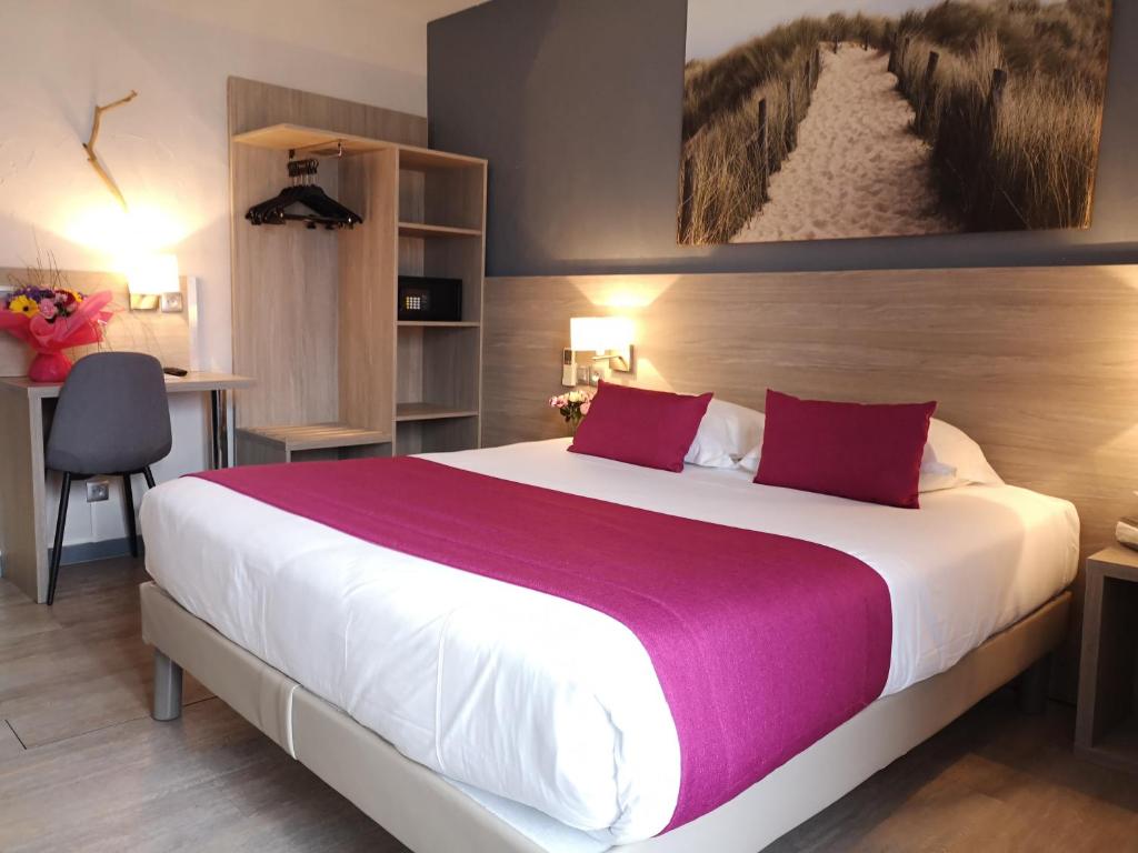 a bedroom with a large white bed with purple pillows at Atoll Hotel restaurant in Fréjus