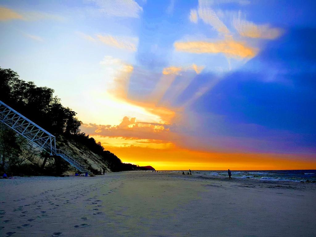 a sunset at the beach with people walking on the sand at Ferienwohnungen ÜckeRitz mit PKW Stellplatz bei Familie Habben-Hollander in Ueckeritz