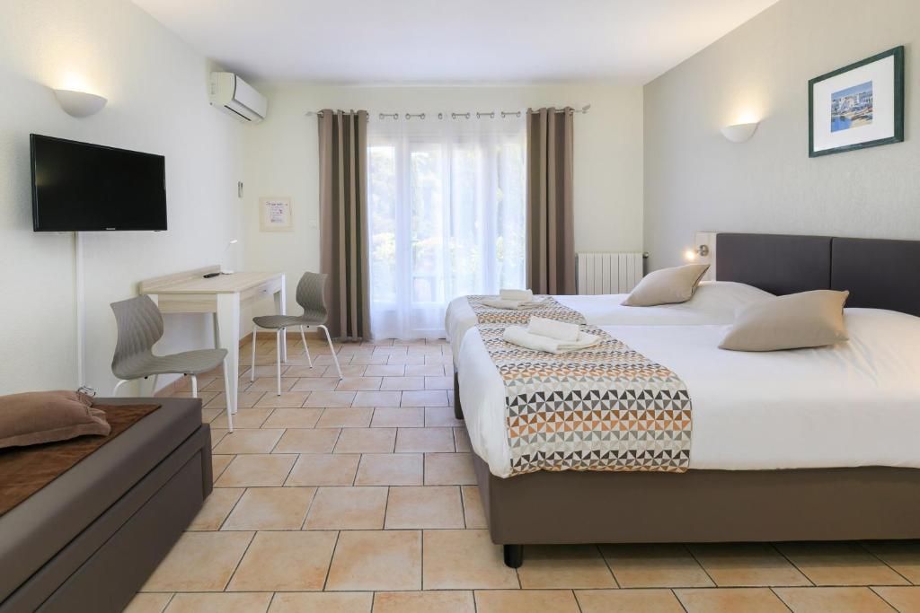 a hotel room with two beds and a desk at Joseph Charles in LʼÎle-Rousse