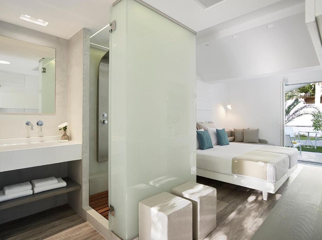 a bedroom with a bed and a sink and a mirror at Kouros Seasight Hotel in Pythagoreio