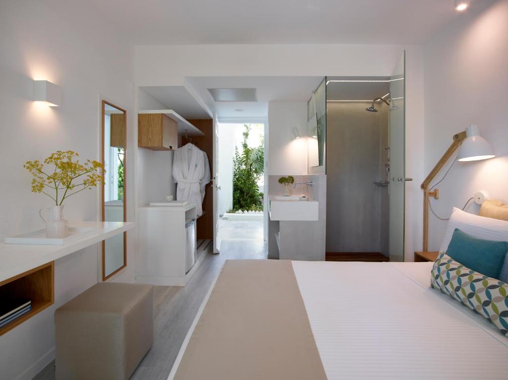 a white room with a bed and a bathroom at Kouros Seasight Hotel in Pythagoreio