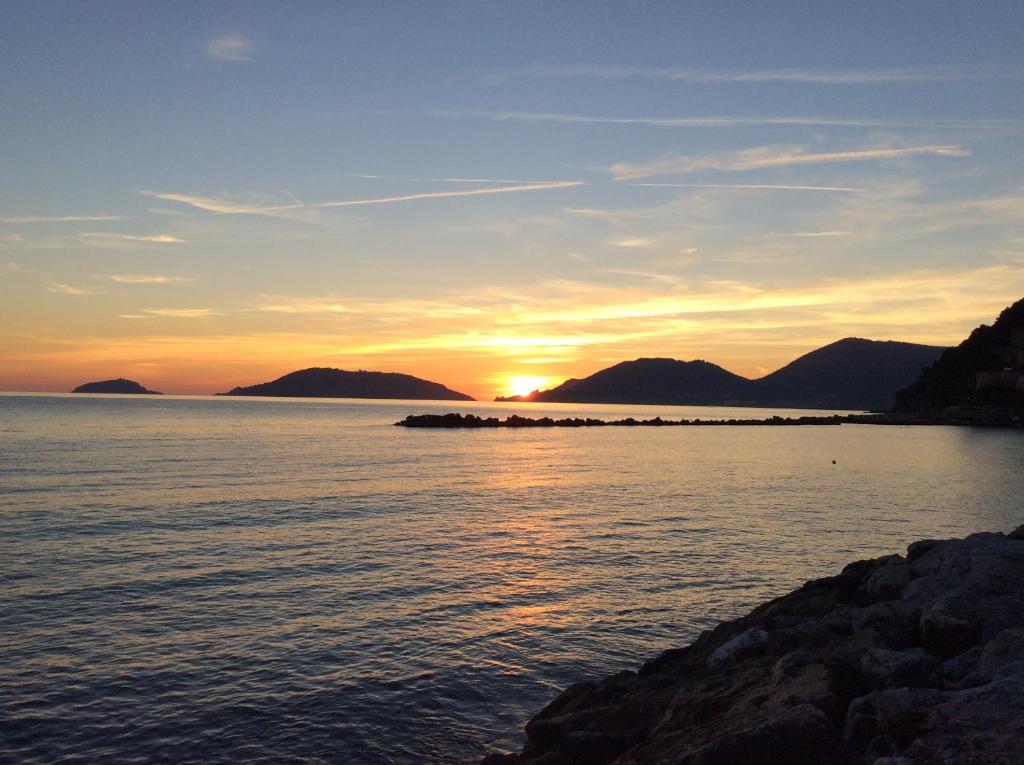 a sunset over a body of water with mountains at Cinqueterre Alla Chetichella in Lerici