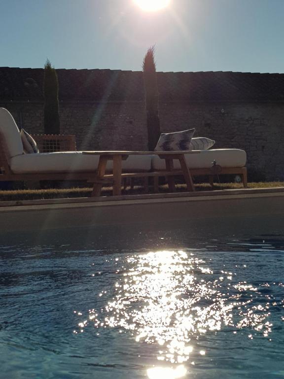 a pool with two chairs and a table next to the water at Les Hauts De Chalonne in Le Gond-Pontouvre