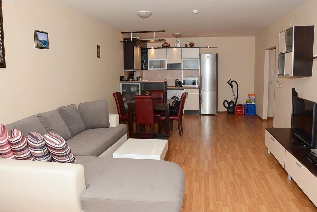 Una sala de estar con un sofá y una mesa y una cocina. en Апартамент София, en Golden Sands