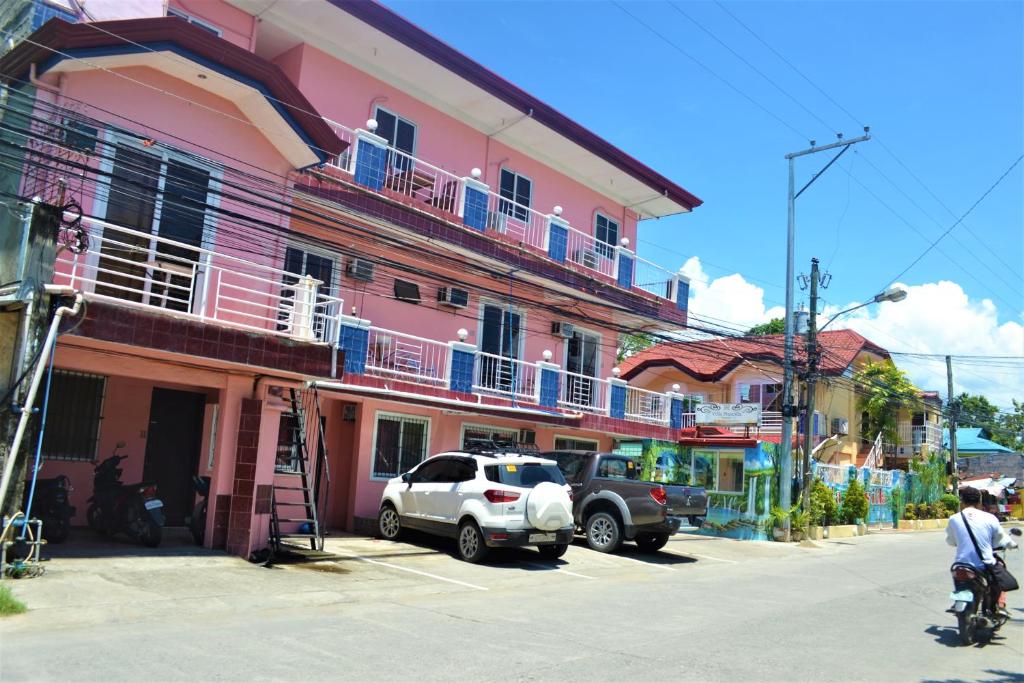 un edificio rosa con coches estacionados frente a él en Villa Prescilla, en Dumaguete