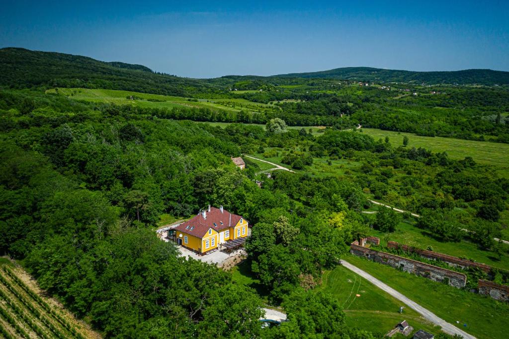 una vista aérea de una gran casa amarilla en un campo en Tusculanum Panzió, en Mindszentkálla