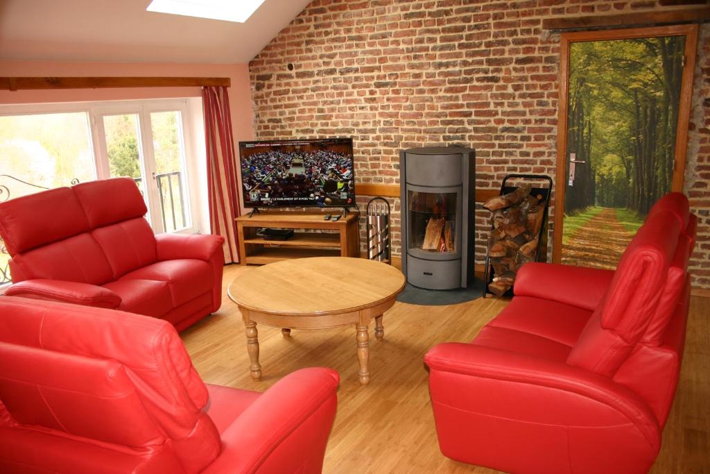 a living room with red furniture and a fireplace at Les Gîtes d'Olloy - Le Roi Cerf in Olloy-sur-Viroin