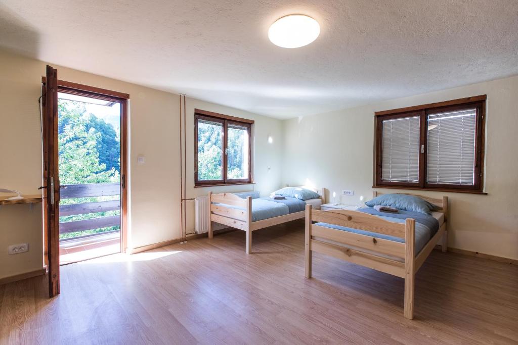 a room with two beds and a table and windows at Dolar Rooms in Bled