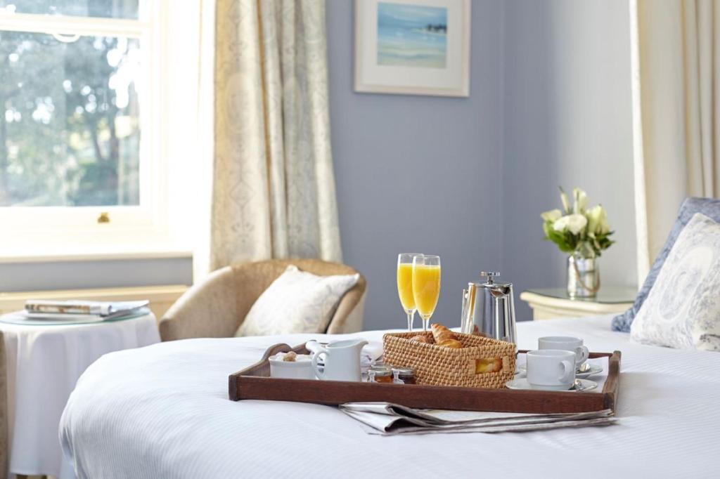 a tray of food and a glass of wine on a bed at The Royal Hotel in Ventnor