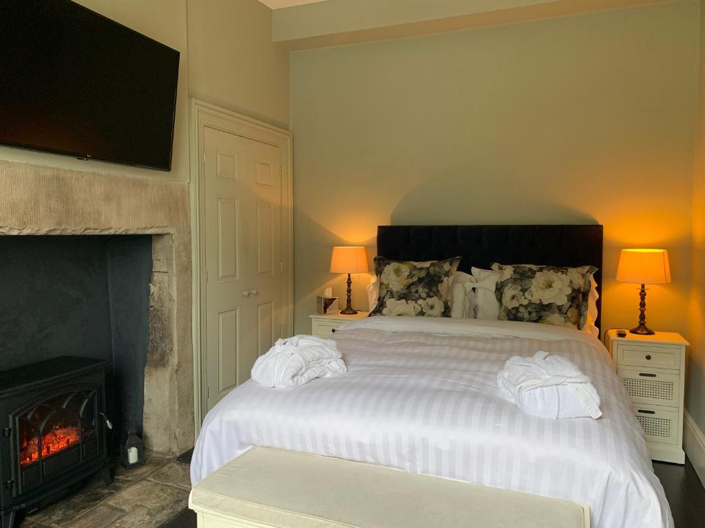 a bedroom with a white bed and a fireplace at Dovenby Apartment- great base for exploring Lake District in Cockermouth