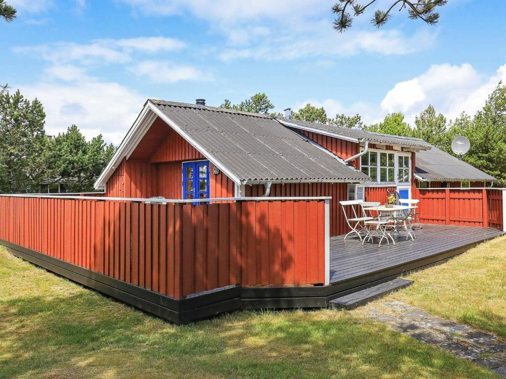 une maison rouge avec une terrasse et une table dans l'établissement 4 person holiday home in Thisted, à Thisted