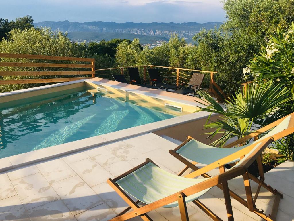 a swimming pool with two lawn chairs and a pair at Four Bedrooms Villa Anita in Polje